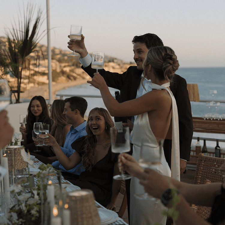 Wedding celebration on the terrace, with guests toasting against a scenic sunset backdrop.